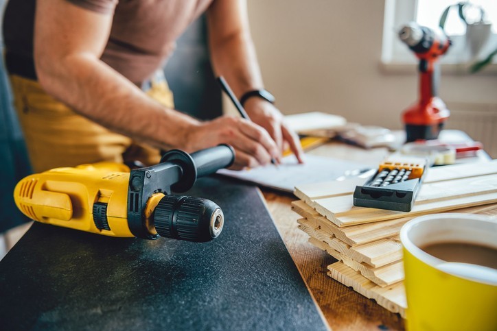 Power drill and Man making draft plan in the background